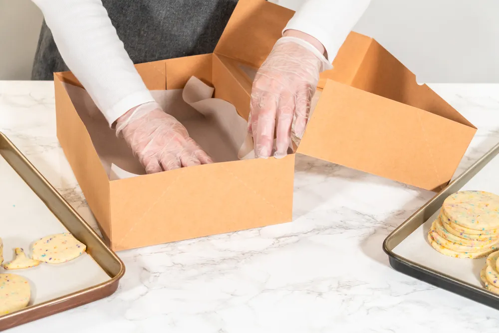 Fotografía de las manos de una mujer armando cajas plegadizas de Carnevali en su oficina.